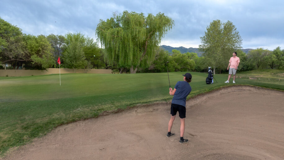 a man chipping out of a bunker on hole 5 of forty niner country club